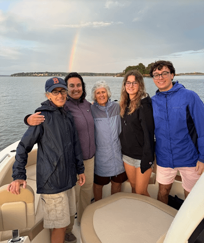 Family posing on an electric boat in front of a rainbow